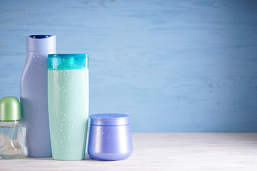 Composition with bottles of body care and beauty products on a wooden background, space for text.