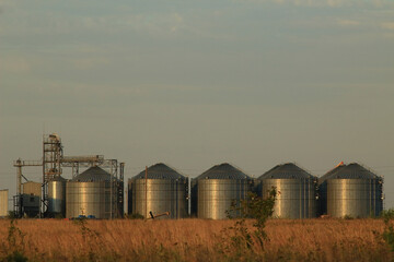  Modern agricultural grain elevator with blue sky on the background and roan on foreground.