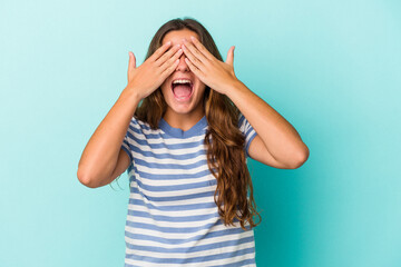 Young caucasian woman isolated on blue background  covers eyes with hands, smiles broadly waiting...