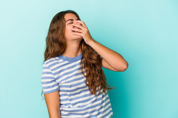 Young caucasian woman isolated on blue background  laughing happy, carefree, natural emotion.