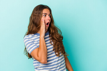 Young caucasian woman isolated on blue background  being shocked because of something she has seen.
