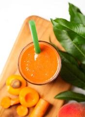 Overhead view of a smoothie made from yellow peach, apricot and carrot with copy space