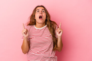 Young caucasian woman isolated on pink background  pointing upside with opened mouth.