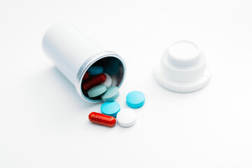 Various medicines from pills and tablets fall out of the container on the table