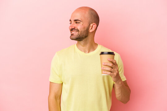 Young Caucasian Bald Man Holding A Take Away Coffee Isolated On Pink Background  Looks Aside Smiling, Cheerful And Pleasant.