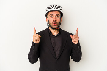 Young business bald man wearing a bike helmet isolated on white background  pointing upside with opened mouth.