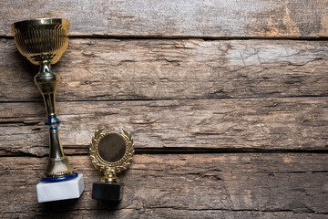 Golden award trophy on the old wooden table flat lay background with copy space.