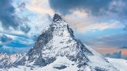 Iconic view of Snowy Matterhorn peak with dramatic clouds, Swiss Alps, Valais, Switzerland.