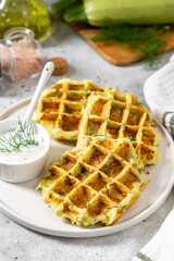Homemade zucchini waffles in a white plate on a light gray culinary background closeup