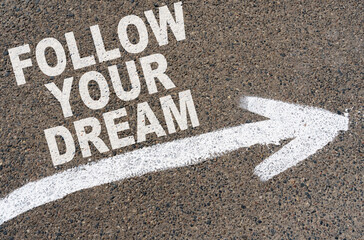 On the asphalt road markings an arrow with the inscription - FOLLOW YOUR DREAM