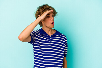 Young caucasian man with make up isolated on blue background  looking far away keeping hand on...