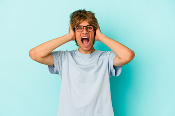 Fototapeta na wymiar Young caucasian man with make up isolated on blue background screaming, very excited, passionate, satisfied with something.