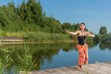 Fototapeta premium Girl with dark hair doing yoga on the lake in summer on a sunny day