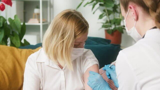 Coronavirus Vaccination close-up, grafting in polyclinic, doctor in protective medical uniform giving injection against covid-19 in arm of woman patient. Nurse using vaccine, prevention virus