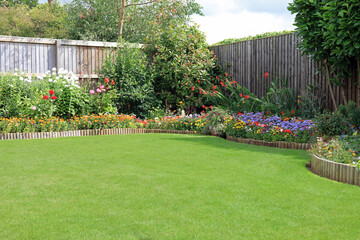 Pretty Colourful Flower Beds Bordering A Well Maintained Lawn. - obrazy, fototapety, plakaty