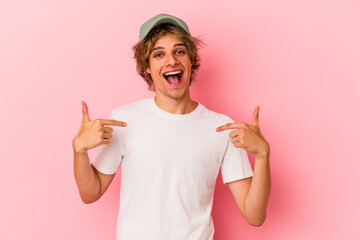 Young caucasian man with make up isolated on pink background surprised pointing with finger,...