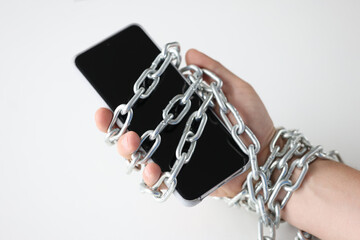 Male hands tied with chain and hold smartphone