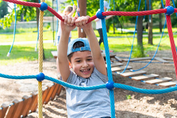 7 year old boy plays on the playground in the summer.