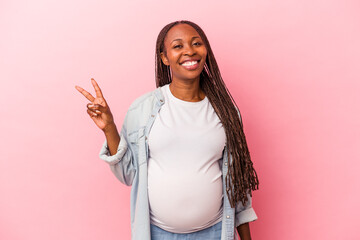 Young african american pregnant woman isolated on pink background joyful and carefree showing a...