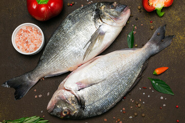 Raw dorado fish with spices and herbs on dark rustic background. 