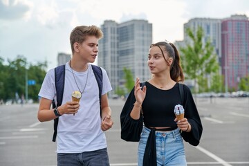 Happy talking couple of teenagers walking together in the city