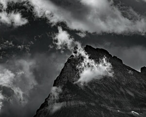  DARK AND ERIE PEAK SURROUNDED BY MOVING CLOUDS AND DARK SKY IN B&W - GLACIER NP