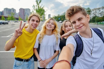 Smiling group of teenagers taking selfie, happy four teens looking at camera