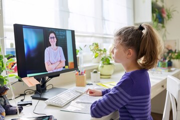 Child preteen girl studying at home using video lesson on computer