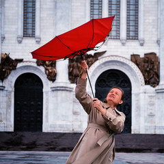 Fototapeta na wymiar Adult woman with a red umbrella during a strong wind in bad weather