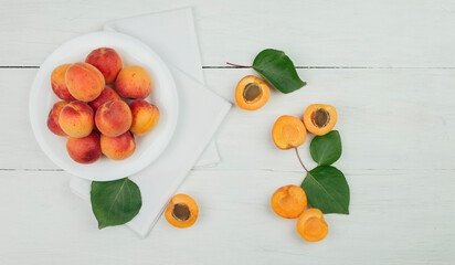 Naklejka na ściany i meble Ripe apricots on the table. wooden background. apricots and green leaves. Flat lay. Top view. Copyspace.