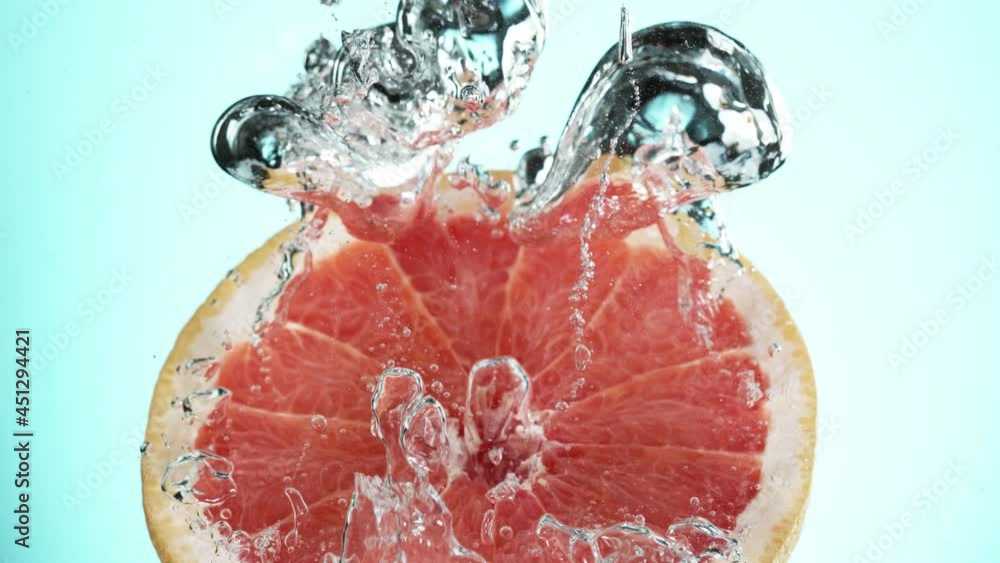Fototapete Super slow motion of falling grapefruit slice into splashing water. Speed ramp effect. Filmed on high speed cinema camera, 1000 fps.