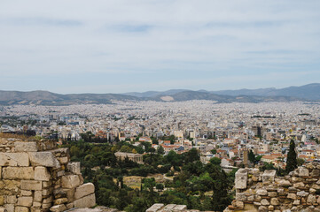 Fototapeta na wymiar Cityscape of Athens at cloudy day. City near hills. Urban architecture in Europe. View from Acropolis hill of The Temple of Hephaestus. Ancient ruins.