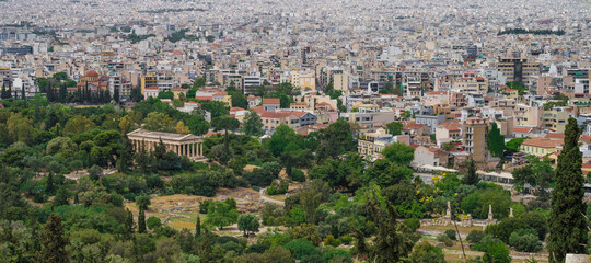 Obraz premium Cityscape of Athens at cloudy day. Urban architecture in Europe. View from Acropolis hill of The Temple of Hephaestus. Green trees.