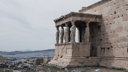 Ancient marble temple on Acropolis hill in Athens, Greece. Caryatids of the Erechtheion. Cloudy sky. Nobody. Landmark of Athens.