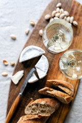 Two glasses of white wine and a wooden board with appetizers on the table.
