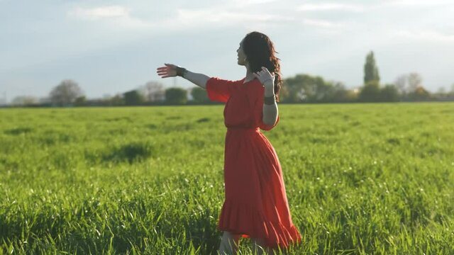 beautiful Spanish brunette woman in red dress dancing at sunset in wheat field