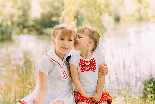 Two girls sisters hug and having fun in the summer in nature