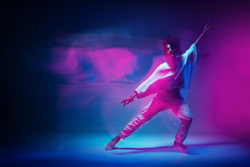 Colourful shot of dancing girl. Female dancer performer show expressive hip hop dance. Colored neon light, long exposure - obrazy, fototapety, plakaty