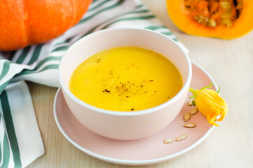 creamy pumpkin soup with vegetables, spice, seeds and croutons in a bowl on light wooden background. Thanksgiving Day. traditional autumn dish, menu on the table. soft focus