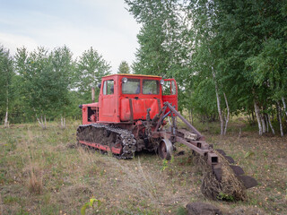 Old tractor in the forest. The tractor is ready to plow the land.