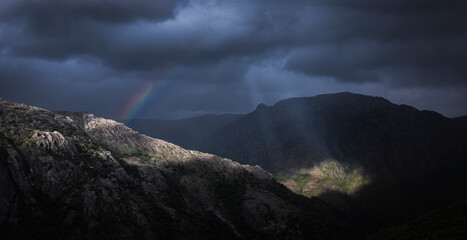 Bonita paisagem dramática nas montanhas  com raio de luz nas nuvens e arco-íris