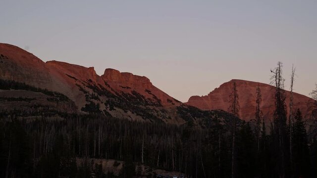 Stunning remote high uinta Rocky Mountain range in Utah in the Uinta National Forest during a gorgeous red vibrant sunset with lone pine trees from a campground on a warm summer evening.