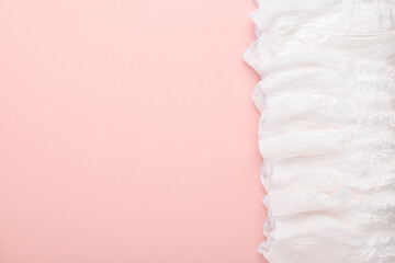 A large stack of disposable diaper panties on a pink background with a place to copy. top view, a place to copy.