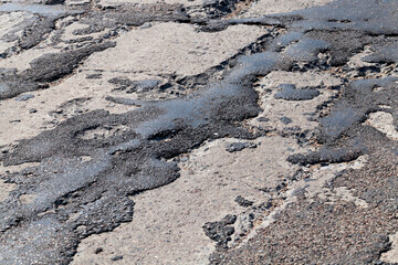 a bad road with poorly repaired potholes and pits