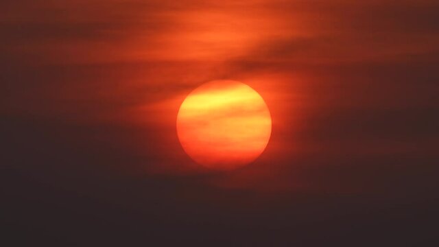 hazy smoky sun with thin clouds and haze try to obscure a hot sun on a summer evening sunset