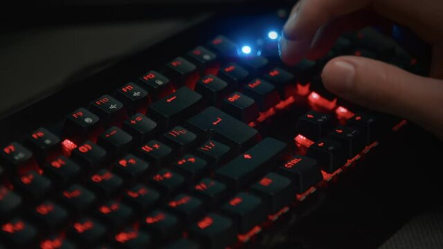 Pressing buttons on a backlit keyboard close-up