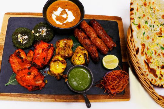 indian food speciality tandoori mix platter, includes chicken tikka, lamb seekh kebab, fish tikka, hara bhara kabab, dal makhani and breads