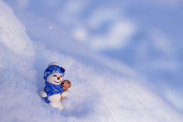 Christmas scene with toy snowman in deep snow close up. Merry Christmas and Happy New Year. Winter card for holidays and celebration.