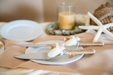 Whimsicle cake serving utensils decorated with seashells,starfish and handle wrapped in twinw at wedding cake table