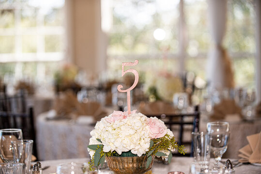 Pink number five guest place indicator sign in flowers at elegant wedding reception table
